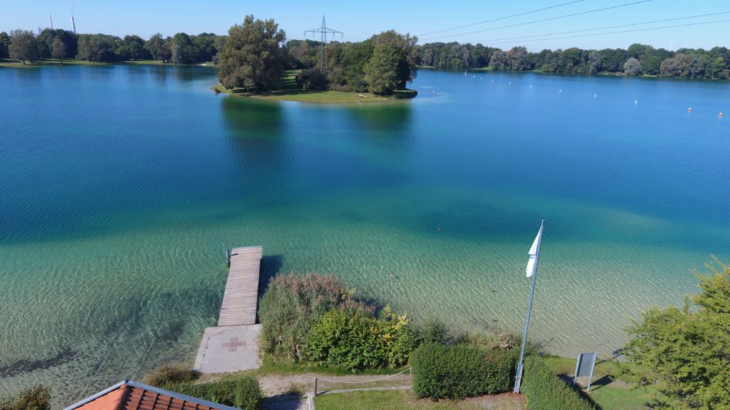 Drohnenbild mit Blick auf dem See. Aufnahmepunkt über der Wasserwachtstation mit dem Bootssteg im Bild